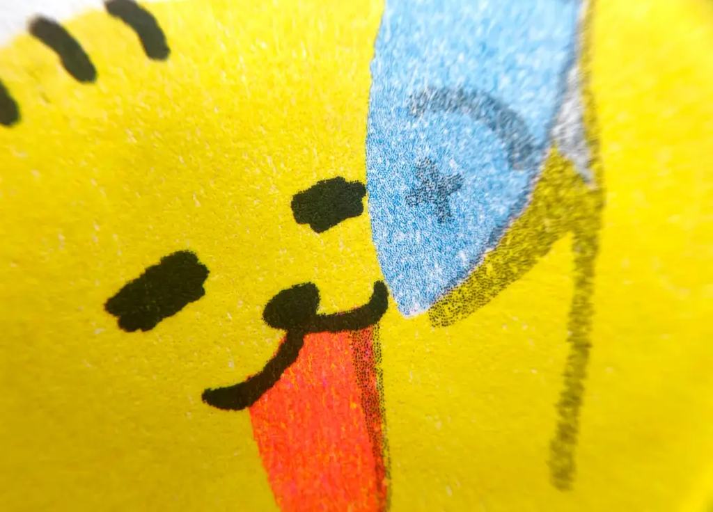 Riso prints up close: halftone dots, two inks overlapping into a third, fluorescent pink on uncoated paper, and the grain showing through.